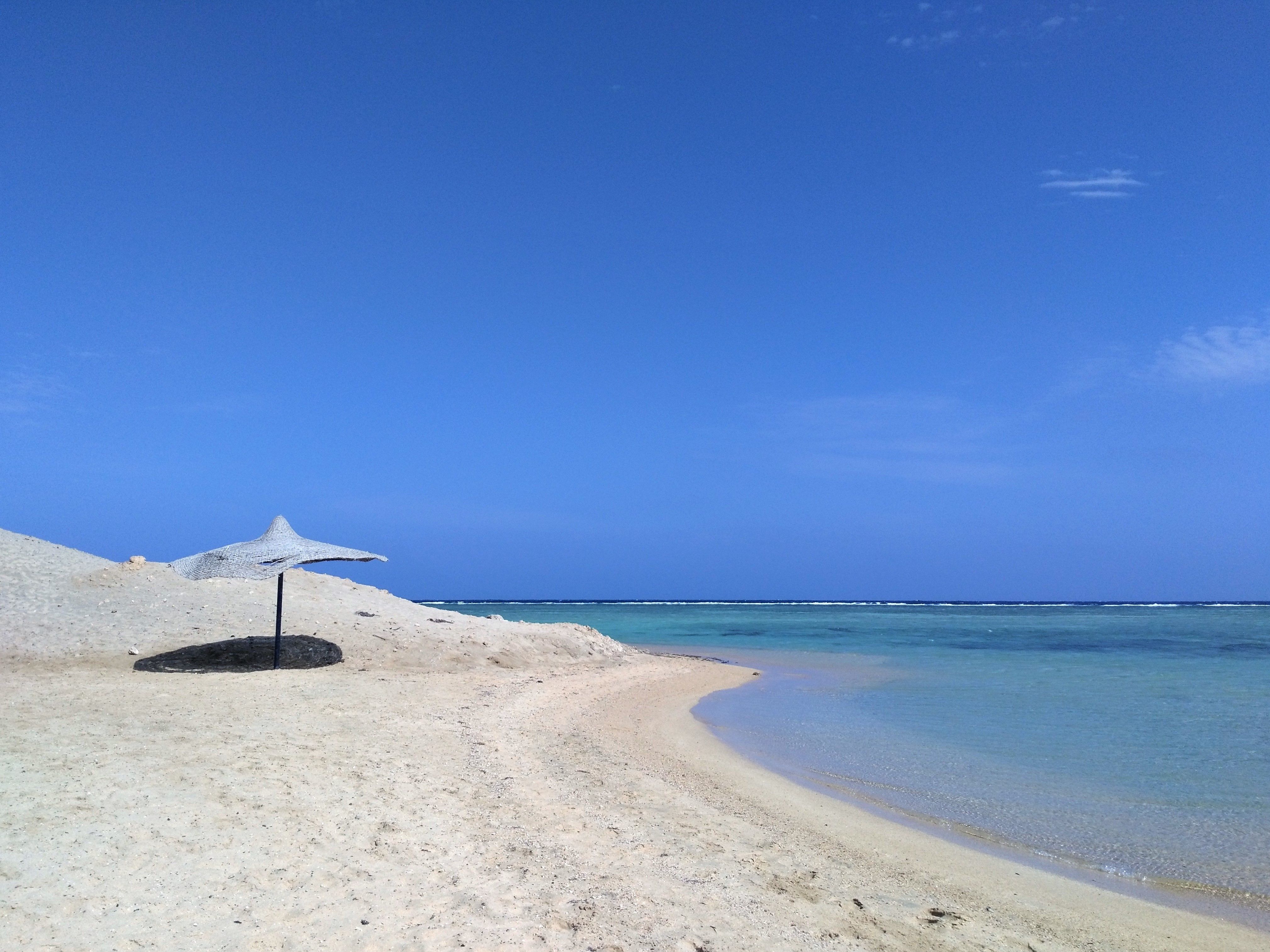 Solo umbrella on white sand beach in El Quseir, Egypt.