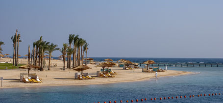 Palm trees and beach umbrellas on Red Sea holiday resort of Port Ghalib in Egypt.