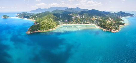 Aerial panoramic view of tropical island of Koh Phangan, Thailand, surrounded by reefs and white sand bays.