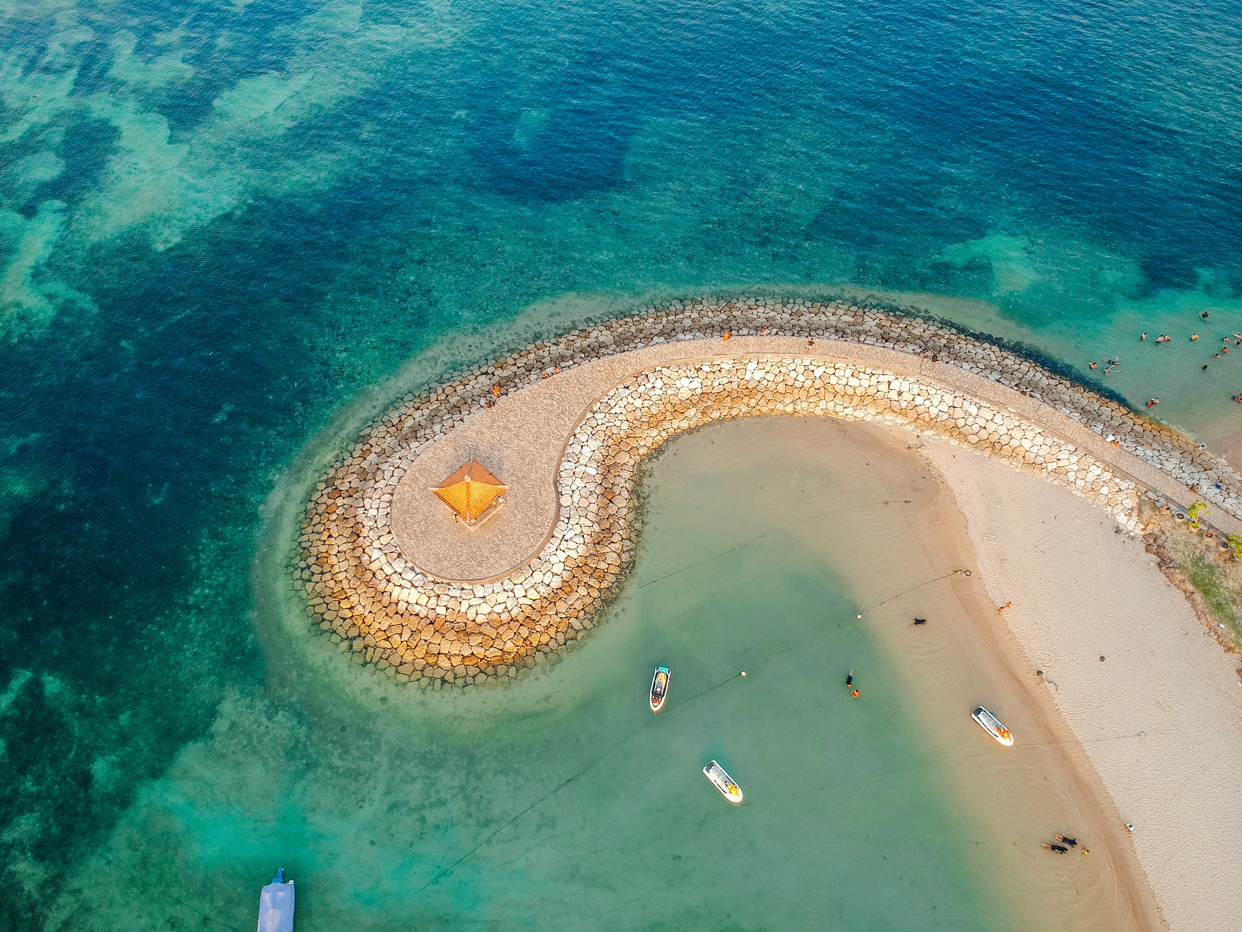 Aerial drone view of spiral shore at Sanur Beach, Bali, Indonesia with Traditional Balinese Fishing Boats blue ocean.