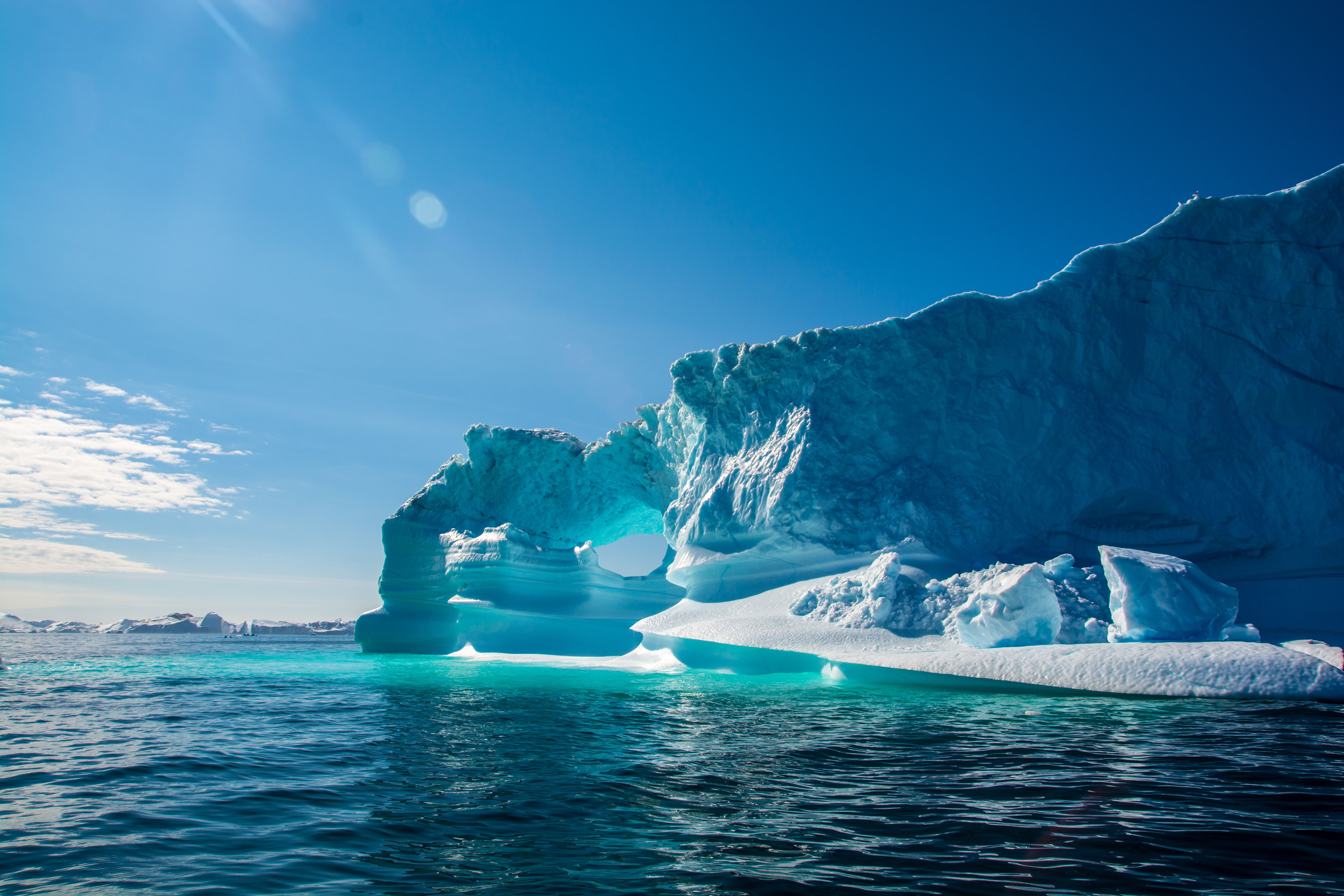 Beautiful icebergs on a sunny day with blue sky and green water in the Arctic Circle. 