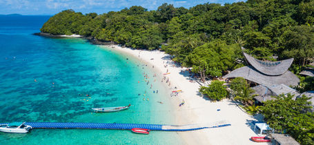 Aerial view of tropical island beach with clear water, jetty and white sand beaches of Koh Hey, Phuket.