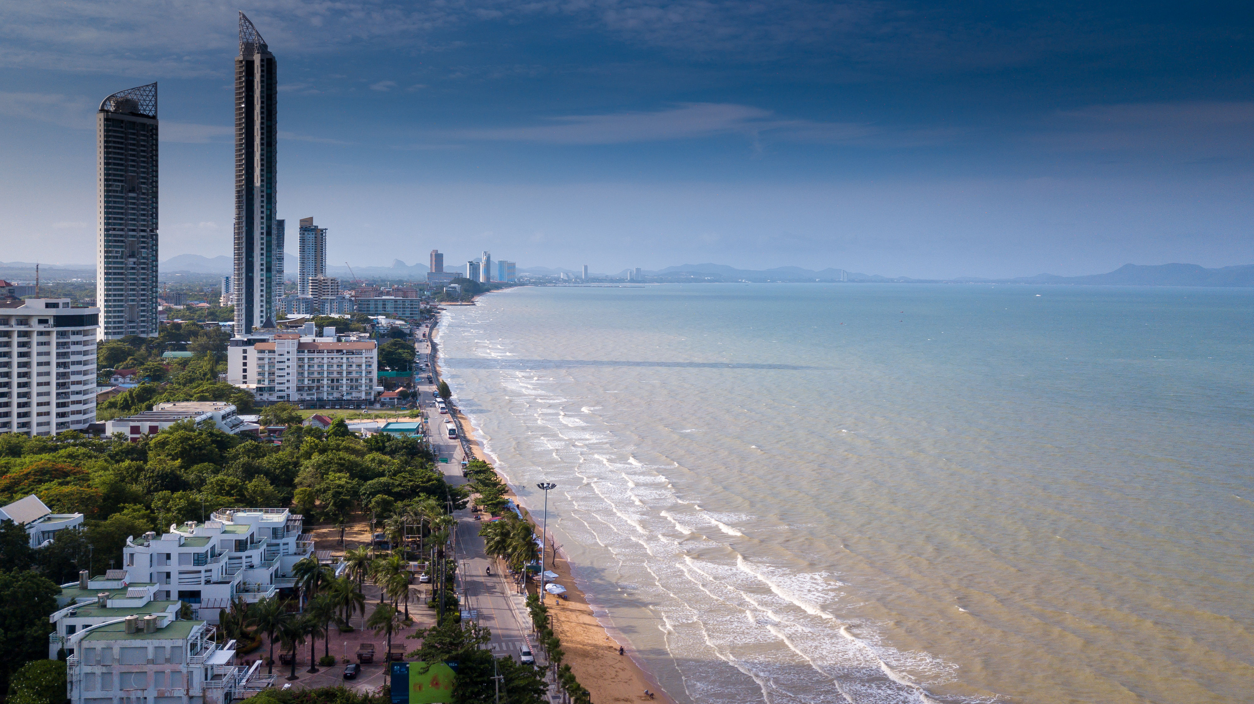 Aerial view of Jomtien Beach with high-rise hotels, golden sand beach and waves on shore. 