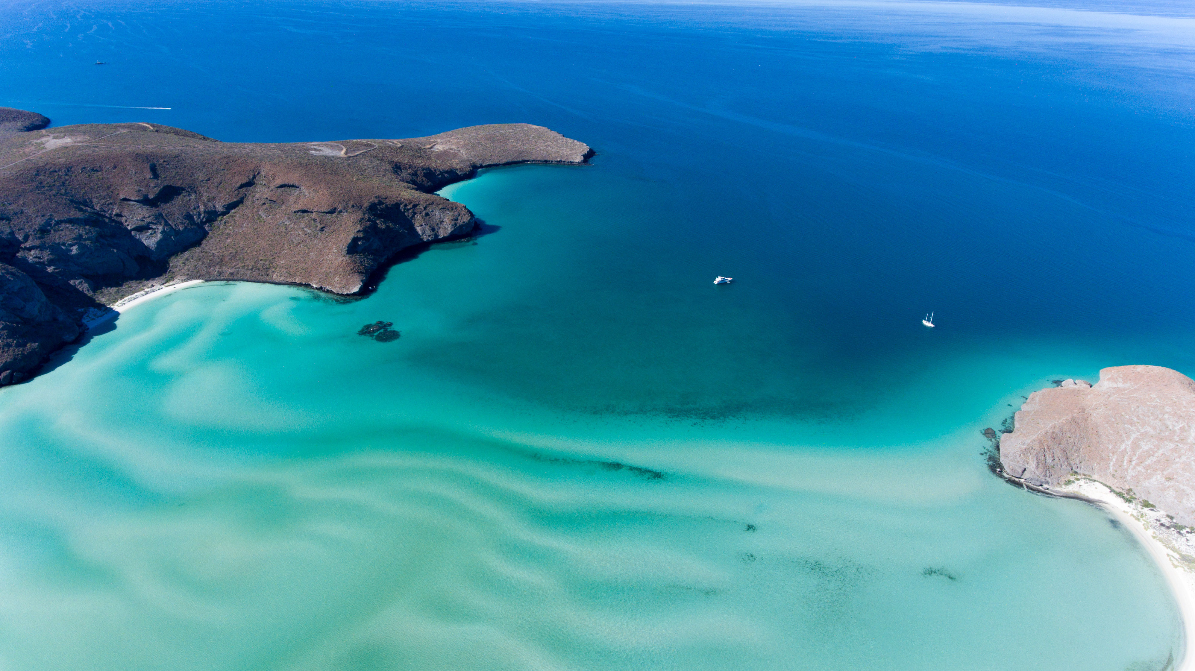 Aerial view of rocky headland, boats and blue waters of Balandra beach, Baja California Sur, Mexico.