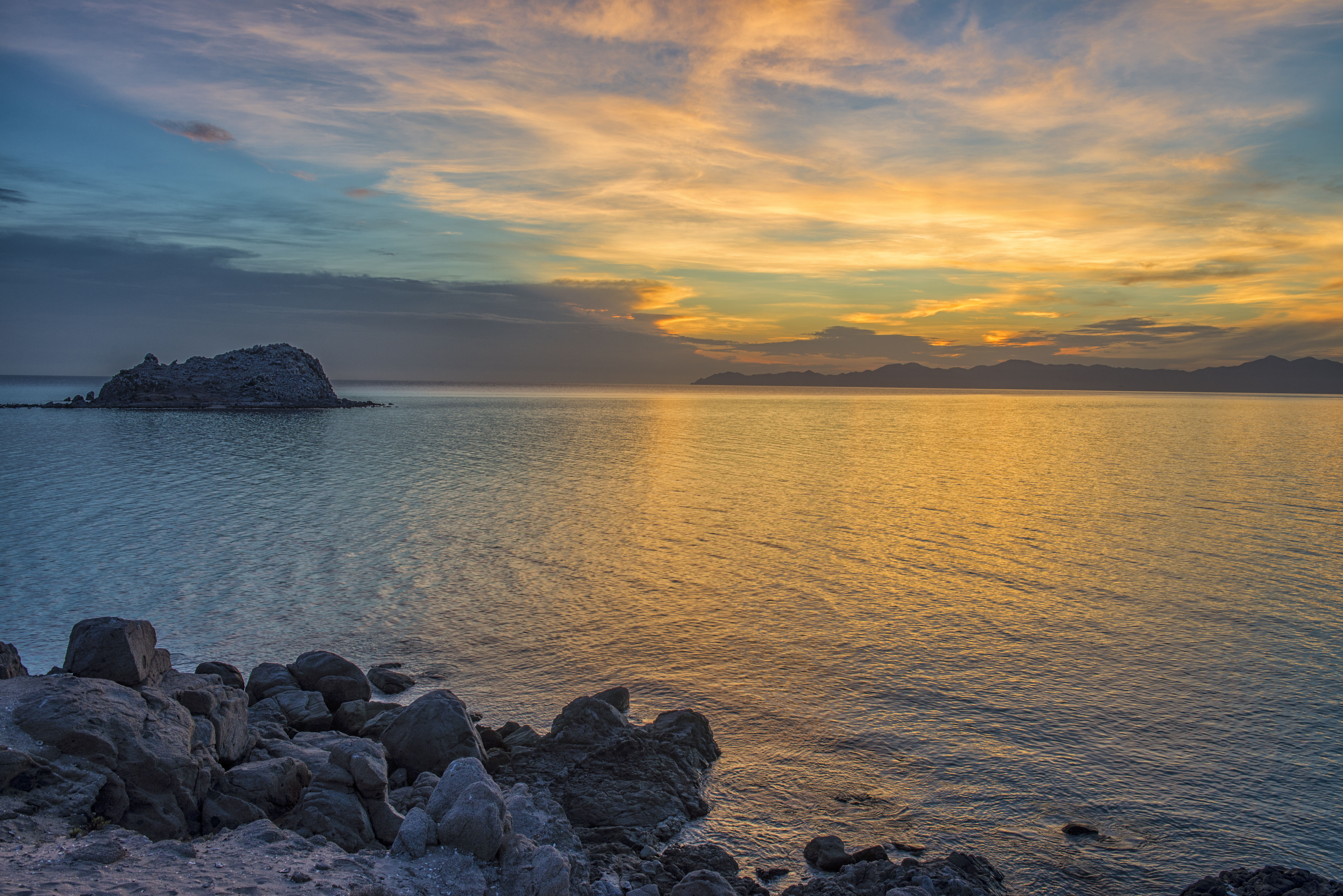 Colourful sunset by rocks and ocean at Ensenada in Mexico. 