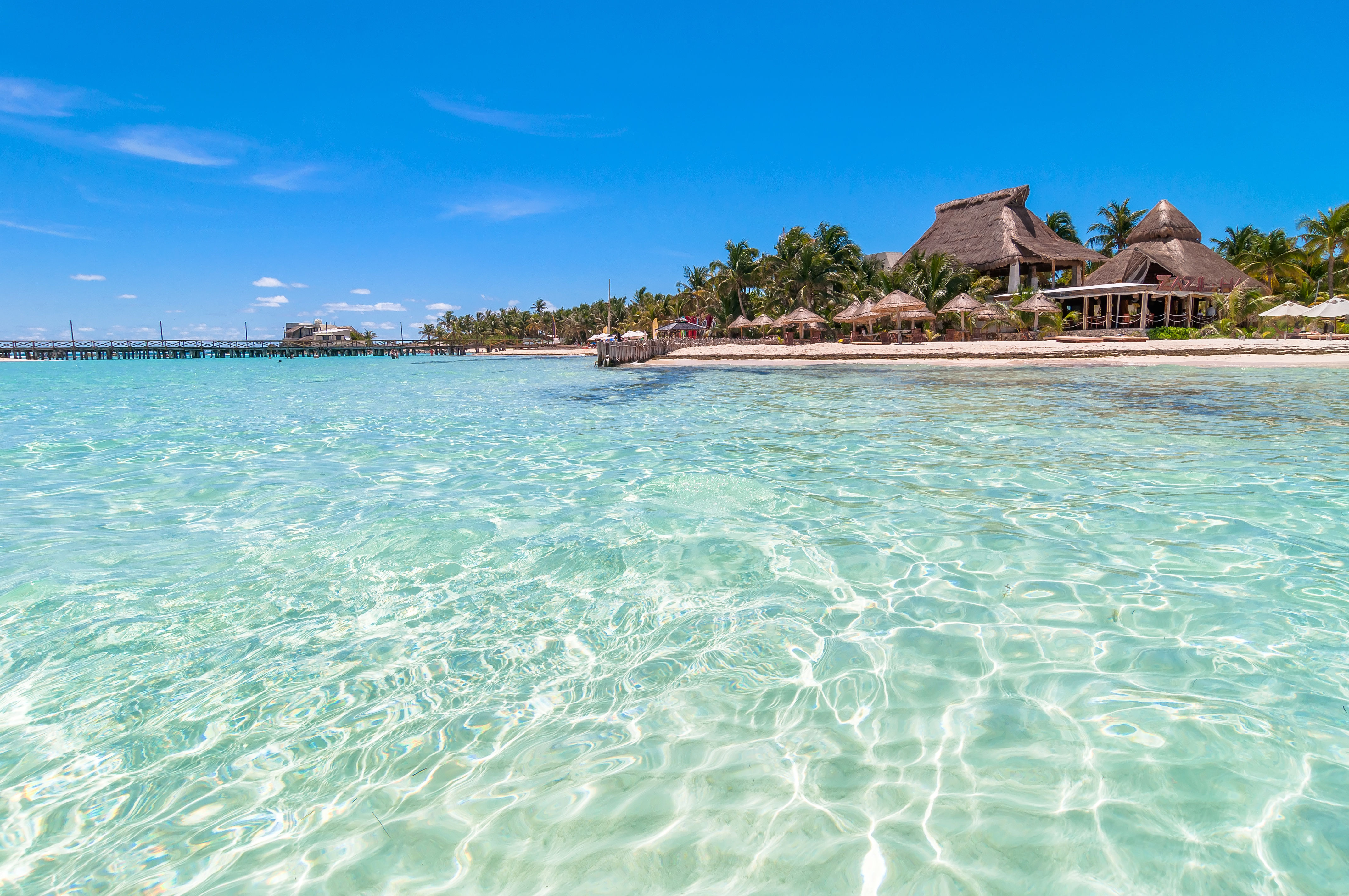 Tropical beach and resort, surrounded by shallow crystal clear waters and wooden jetty in Quintana Roo, Mexico. 