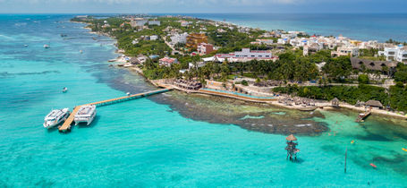 Aerial view of Isla Mujeres beaches, resorts, tropical waters and cruise boats. 