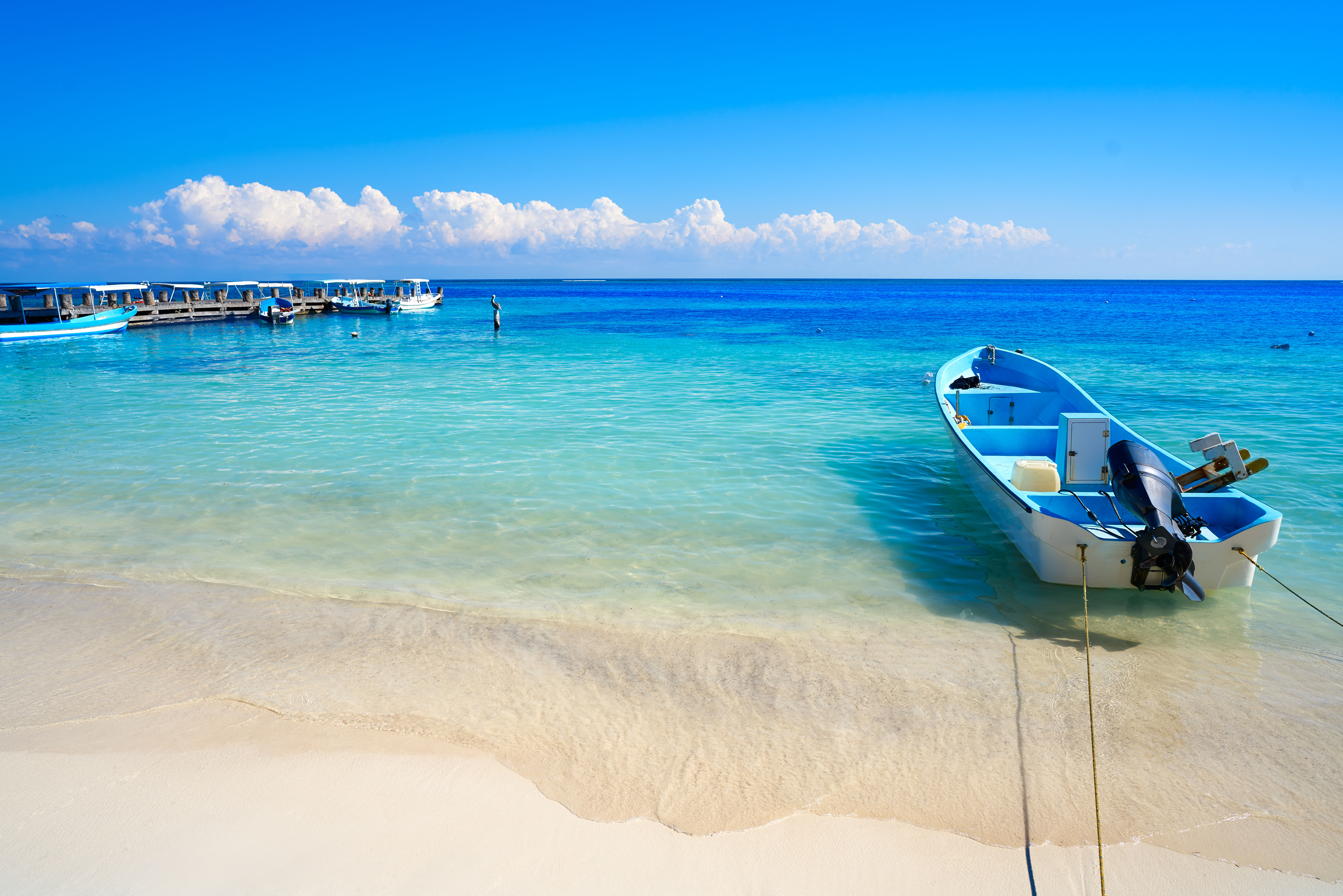 Boats moored on tropical Puerto Morelos beach with crystal clear blue water. 