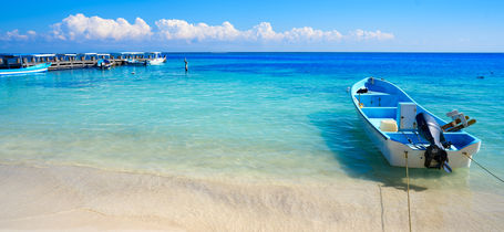 Boats moored on tropical Puerto Morelos beach with crystal clear blue water. 