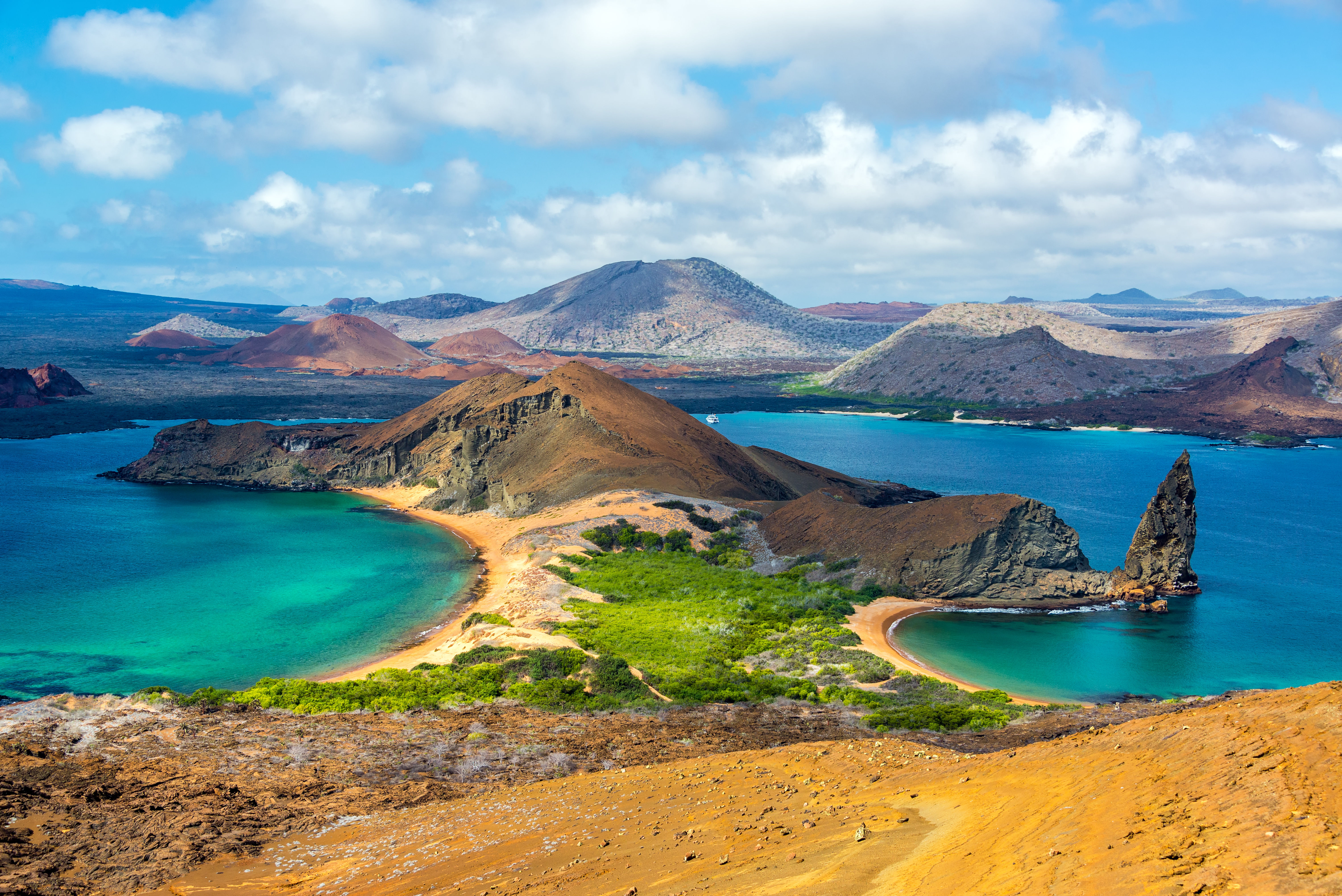 Aerial panorama view from Bartolome Island in Galapagos with rocky hills, green grass and blue waters. South America
