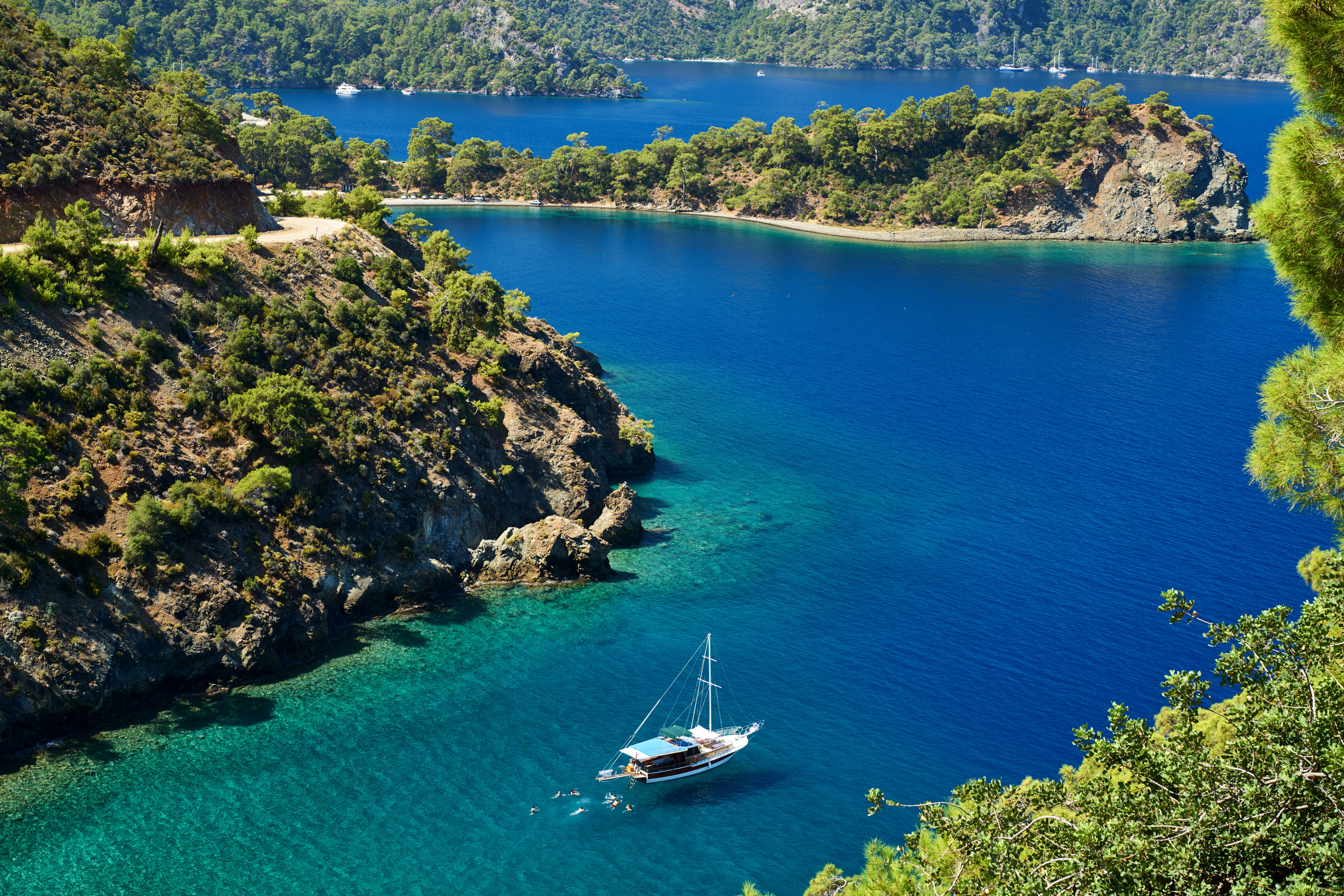 Sail boat in between lush green hills on blue waters in Turkey. 