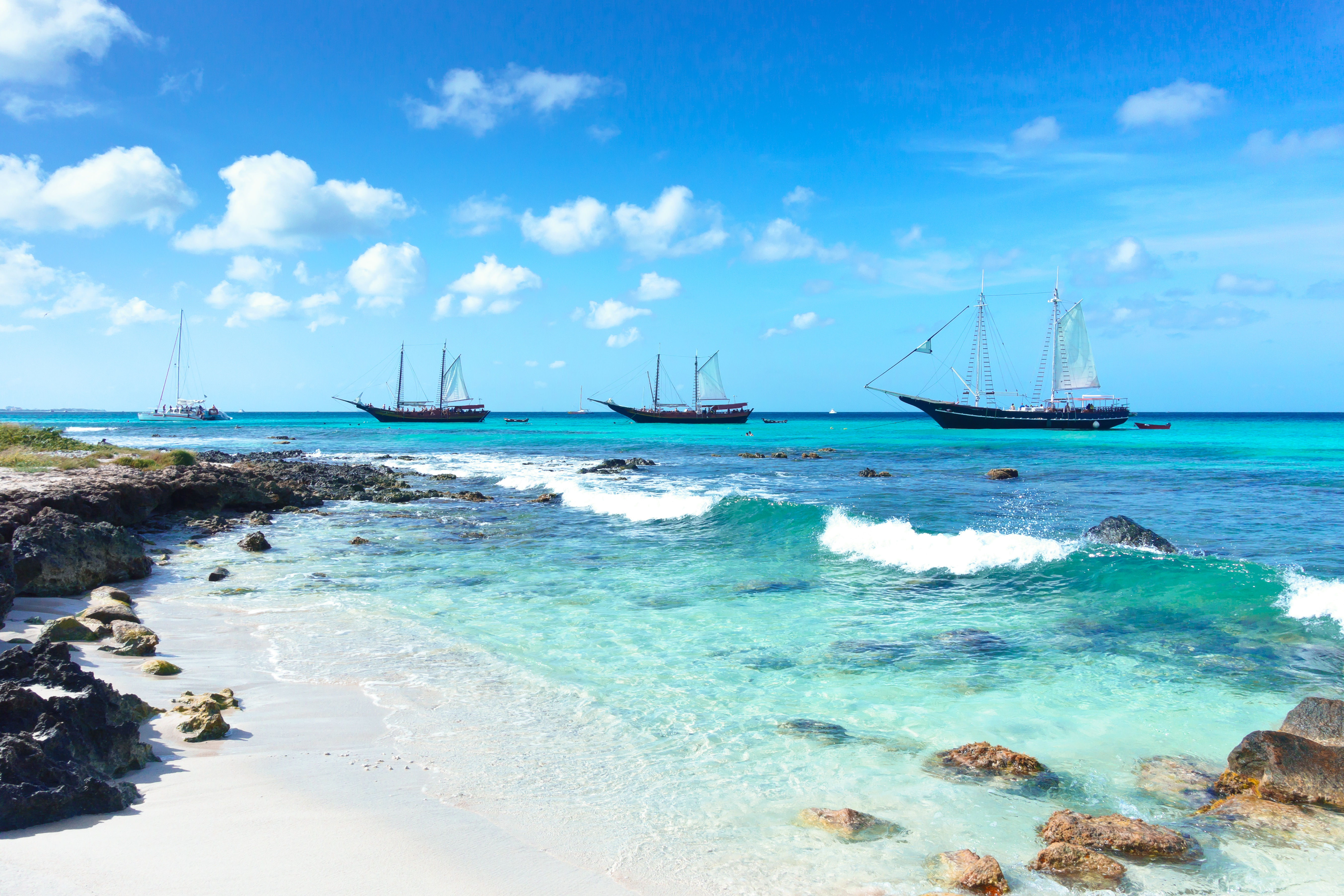 Sail boats next to tropical island in the Caribbean island of Aruba. 