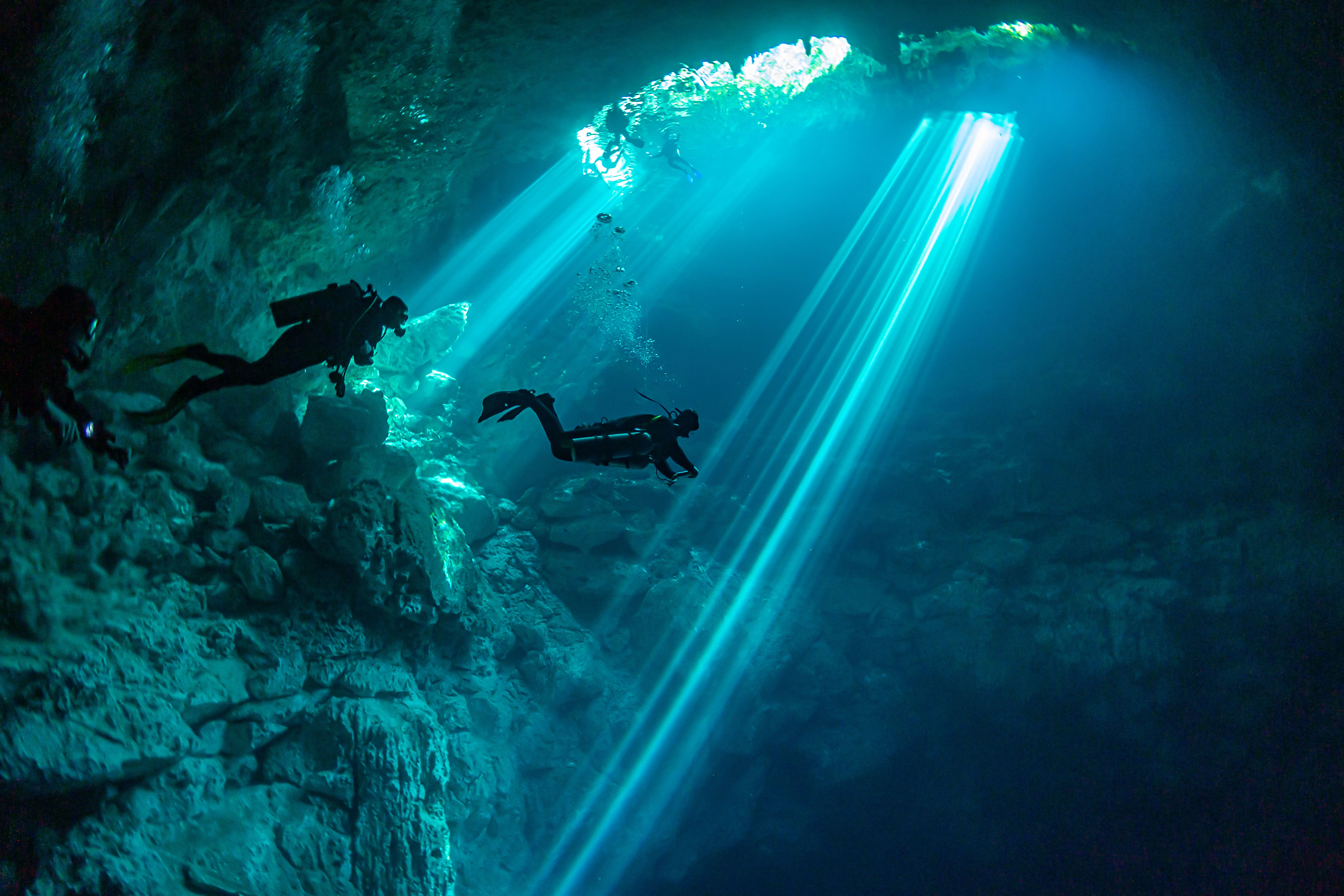 Silhouette of three scuba divers in underwater Cenote in Yucatan, Mexico. 