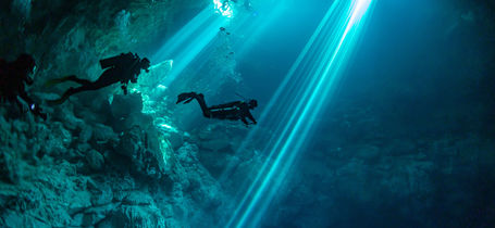 Silhouette of three scuba divers in underwater Cenote in Yucatan, Mexico. 