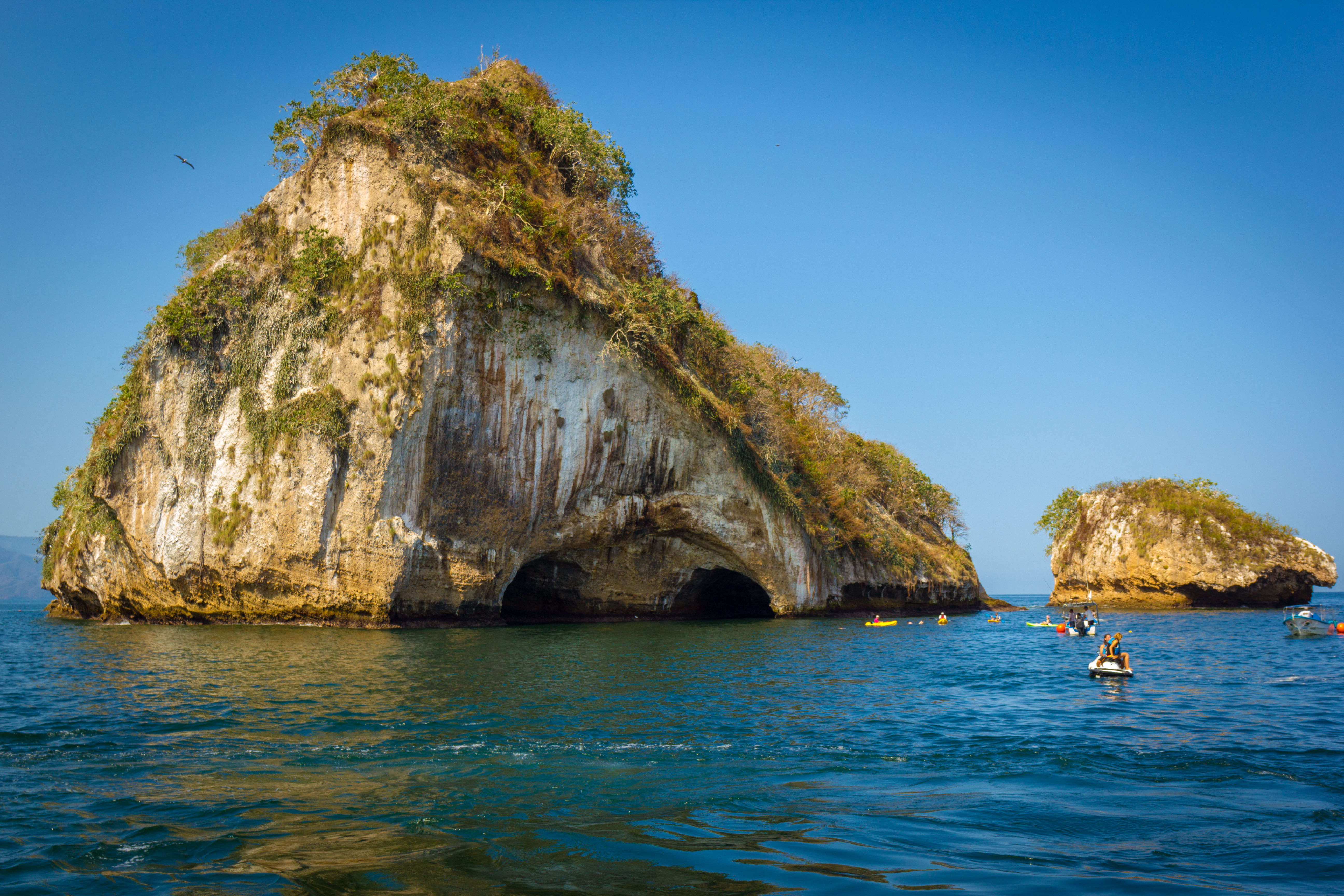 A big and small rock islands surrounded by blue water and kayakers in Jalisco, Mexico. 