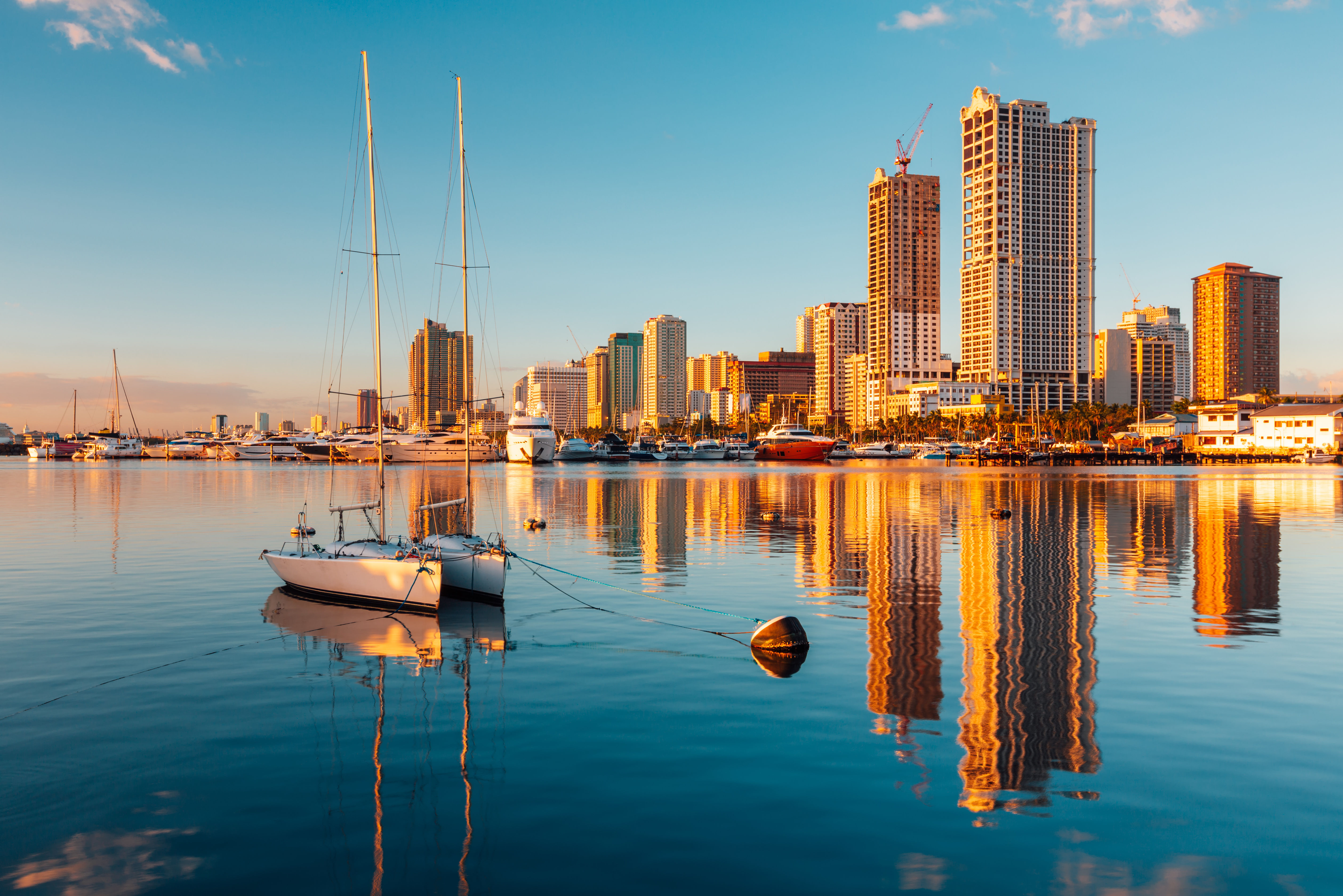 Beautiful panorama view of Skyline of Manila City and Manila Bay with boat and reflections of city in the water.