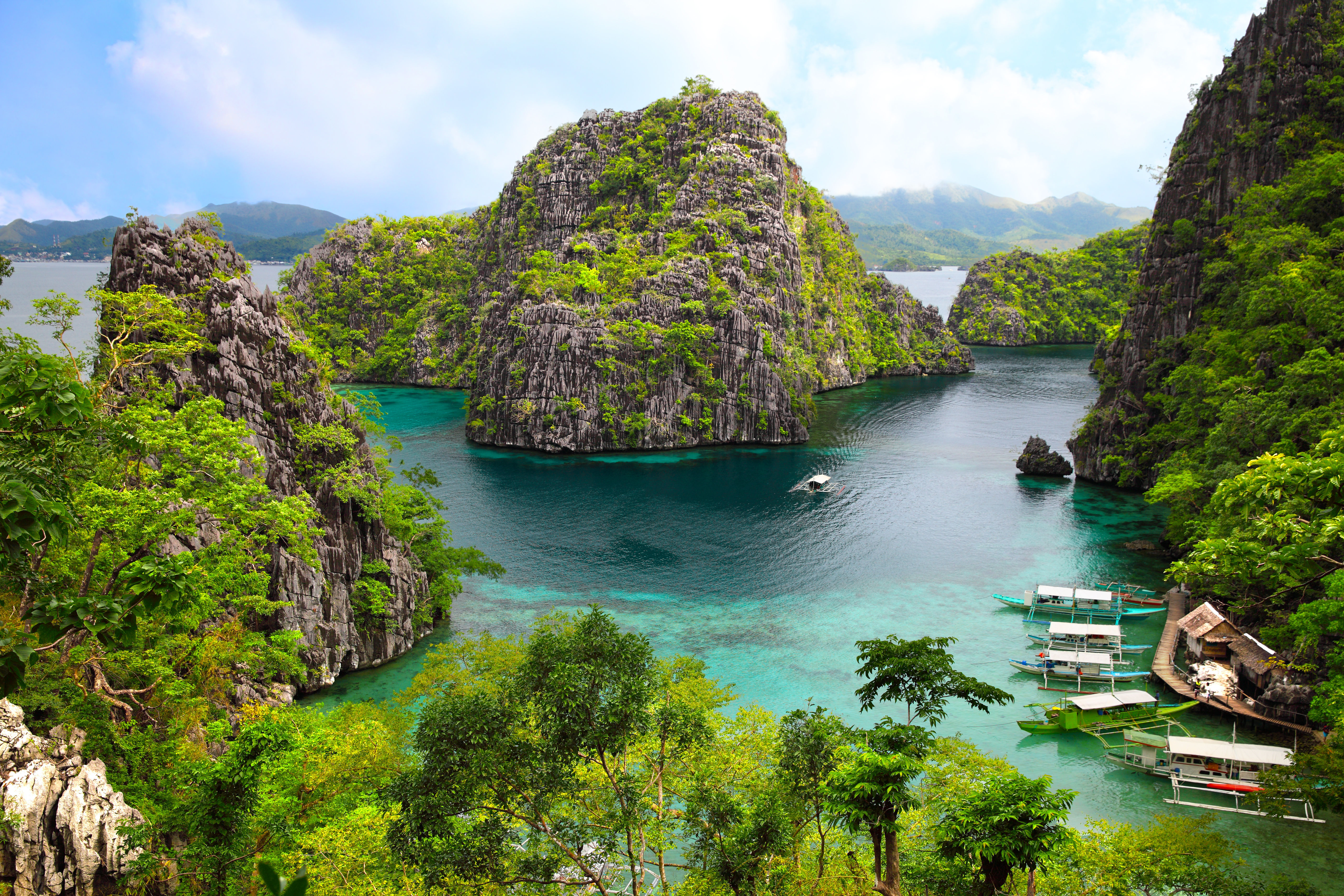 Landscape of view of Busuanga island with green rocky outcrops, blue waters and moored boats. 