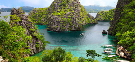 Landscape of view of Busuanga island with green rocky outcrops, blue waters and moored boats. 