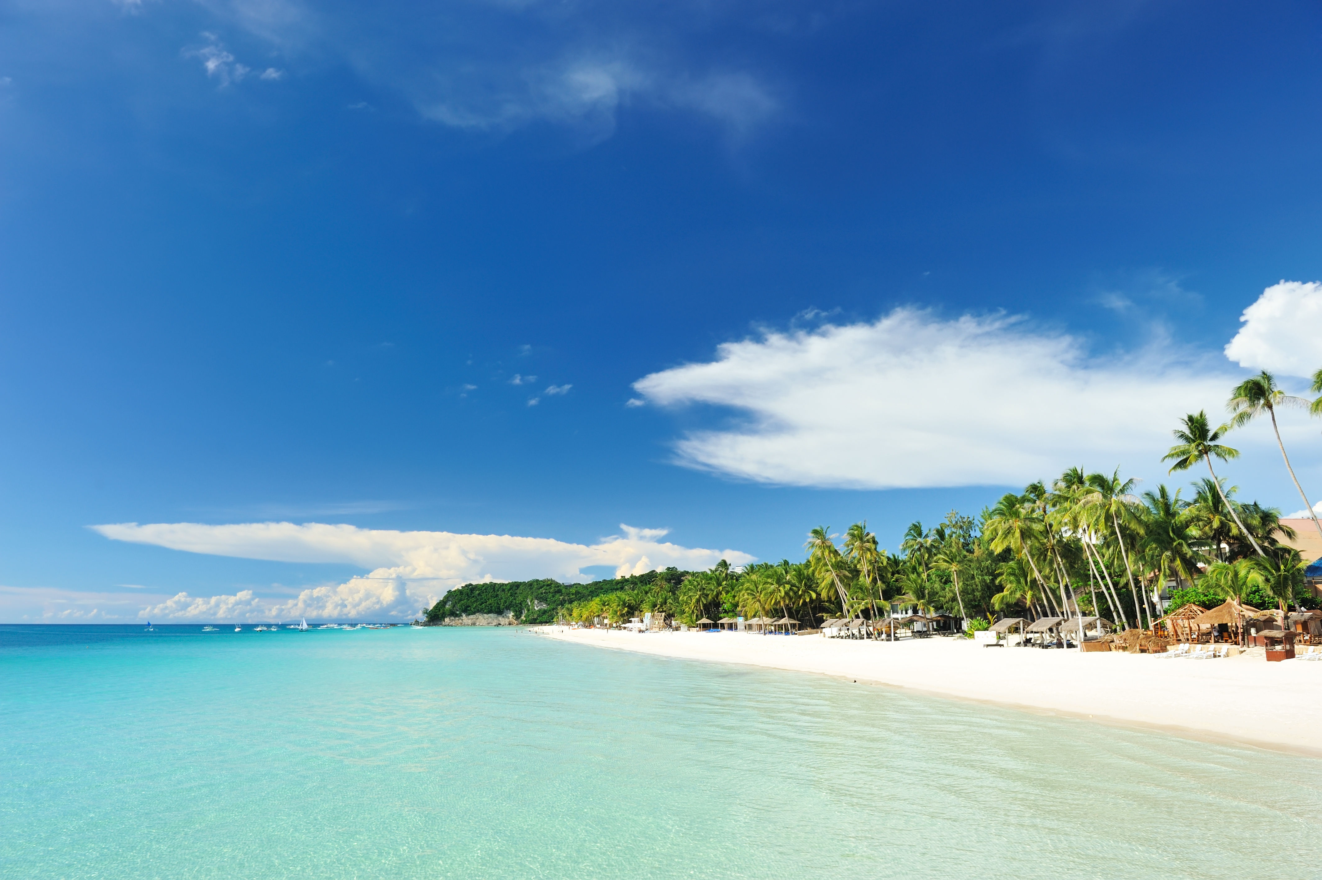 Beautiful pristine white beach with green trees and crystal clear turquoise water in Boracay, Philippines.