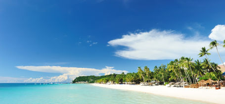 Beautiful pristine white beach with green trees and crystal clear turquoise water in Boracay, Philippines.