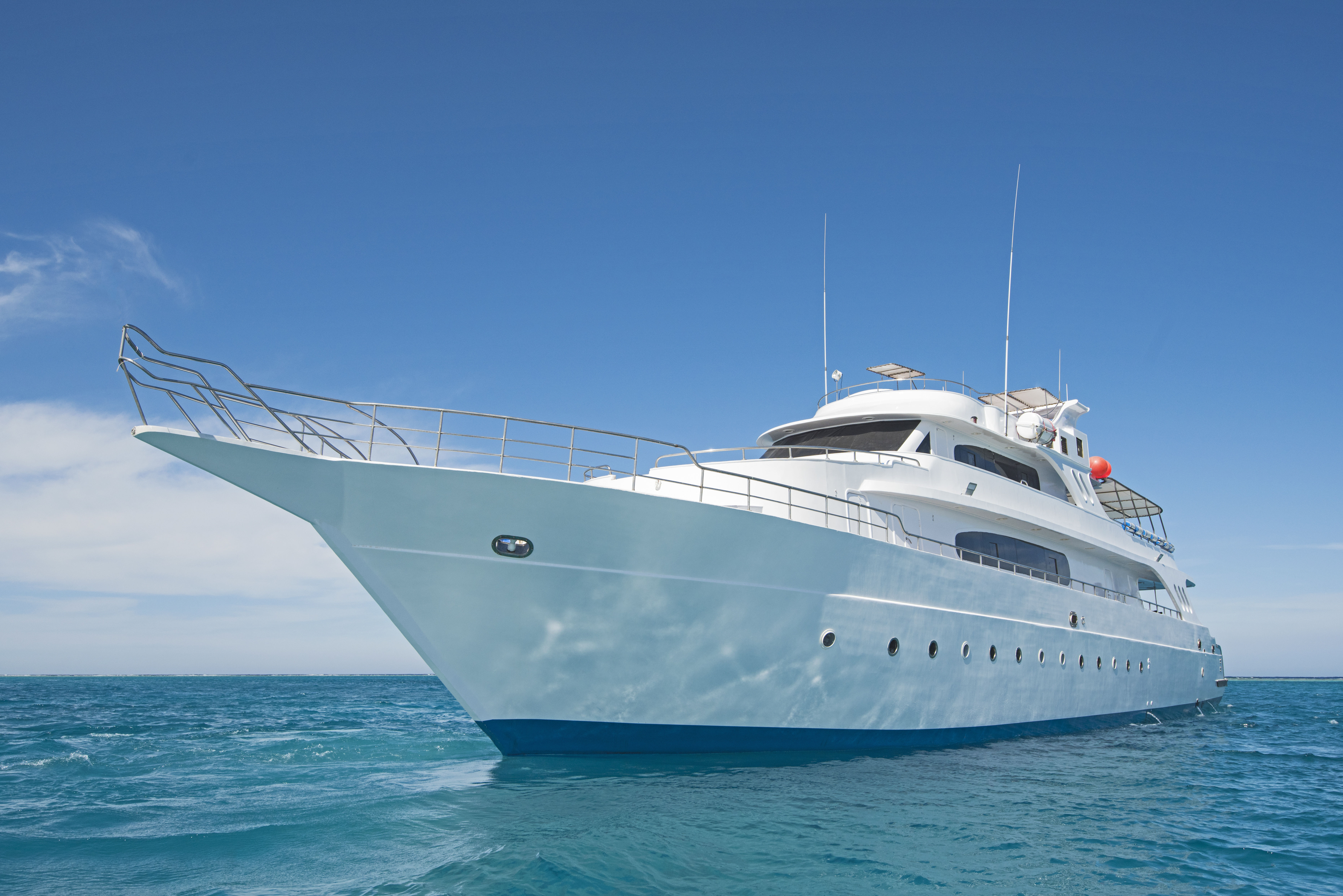 Beautiful white motor yacht scuba diving liveaboard on calm blue sea with clear blue skies.