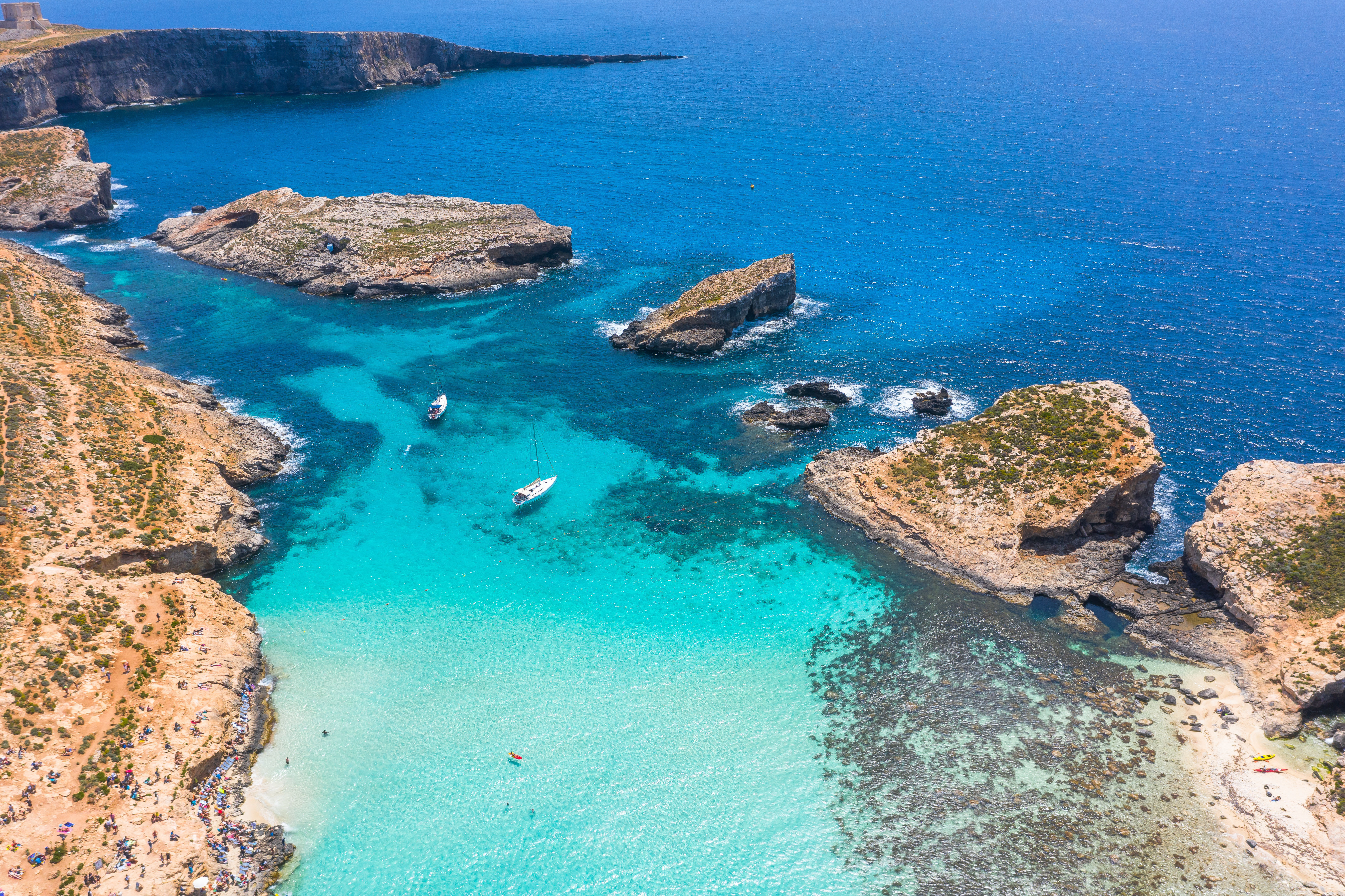 Aerial view of the clear turquoise waters and rocky outcrops of Blue Lagoon on Comino Island in Malta