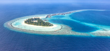 Aerial drone view of Maldivian Ari Atoll with white sand and turquoise waters.
