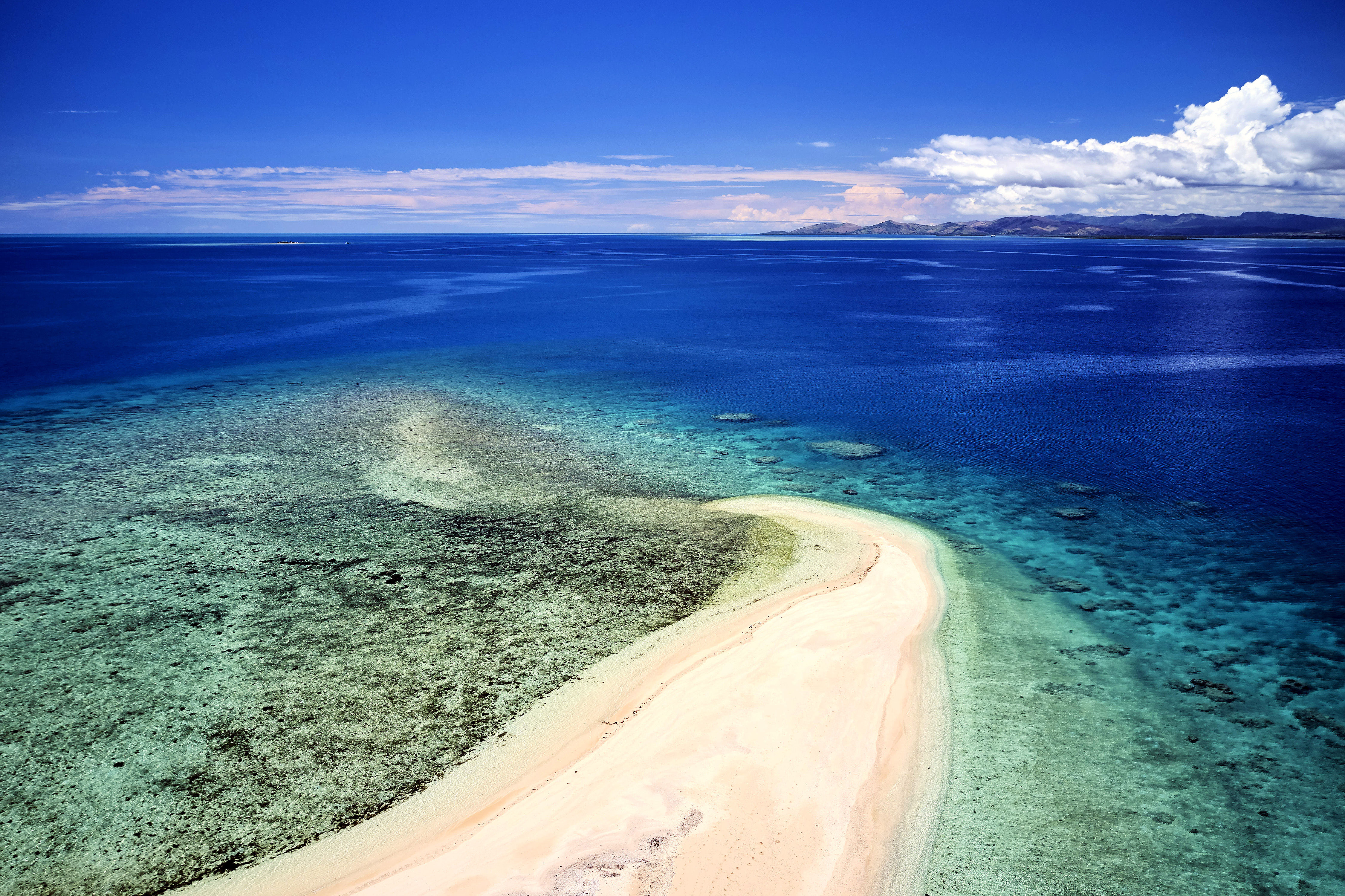 Aerial view of remote island in Fiji overlooking blue coral reef